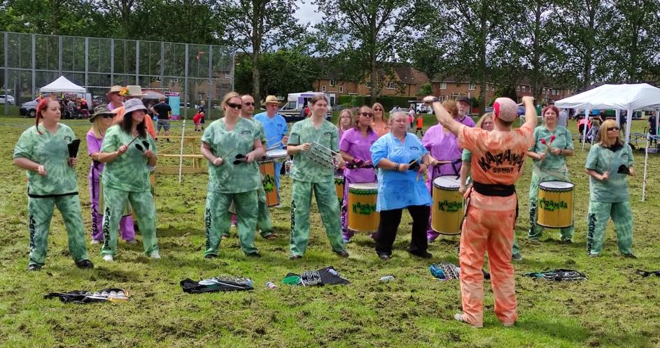 An image showing the Karamba Samba group performing at last year's Blacon Festival. They are dressed in bright colours and are holding drums and other musical instruments.